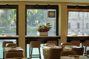 a dining room with tables and chairs and windows at Hotel Bell'arrivo by Dori in Peschiera del Garda