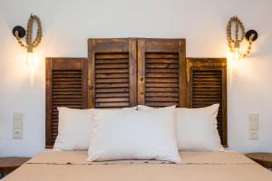 a bed with a wooden headboard and white pillows at Studios Lotos in Potos