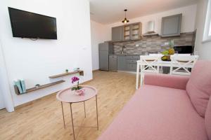 sala de estar con sofá rosa y mesa en Apartmani Rustica, en Drasnice