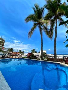 una piscina con palmeras en el fondo en One Beach Street Zona Romantica Puerto Vallarta, en Puerto Vallarta