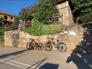 Pétra的住宿－Stonehouse 2 Bedroom Chalet on Olympus Amazing View，三辆自行车停在石墙旁边
