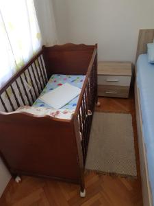 a baby crib with a bed and a dresser in a room at Apartment Skale in Senj
