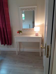 a white dressing table with a mirror and a lamp at Lettermore 1 Apartment in Rathdrum