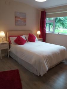 a bedroom with a large white bed with red pillows at Lettermore 1 Apartment in Rathdrum