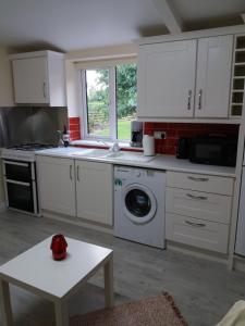 cocina con armarios blancos, lavadora y secadora en Lettermore 1 Apartment, en Rathdrum