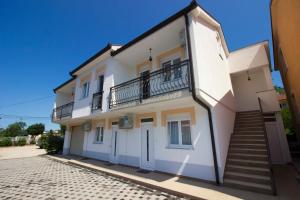 a white building with a balcony and stairs at Guest house Blagaj in Blagaj