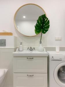 a bathroom with a sink and a mirror and a plant at Apartament Grunwaldzka in Sopot