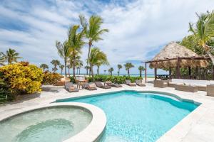 una piscina con sillas, palmeras y el océano en Caleton - Ocean View Villa with Pool, Chef, Butler & Maid en Punta Cana