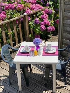una mesa blanca y sillas con flores en una terraza en Comme une évidence gite et chambres d'hotes, en Saint-Vincent-sur-Jard