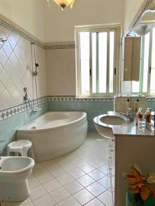 uma casa de banho com 2 lavatórios, uma banheira e um WC. em Portopalo Il Viaggiatore em Portopalo