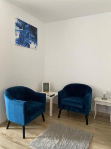 two blue chairs in a living room with a table at Take PRO Timisoara Apartment in Timişoara