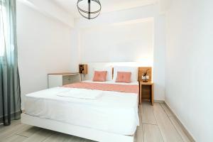 a white bedroom with a bed and a window at Design Suites Efharis (Sauvignon) in Nea Peramos