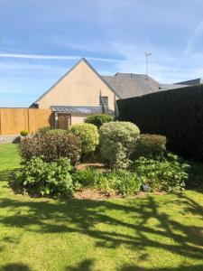 un patio con algunos arbustos y una casa en Hôtel Le Gue Du Holme en Saint-Quentin-sur-le-Homme