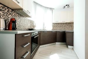 a kitchen with white and brown cabinets and a window at Design Suites Efharis (Sauvignon) in Nea Peramos +19 photos