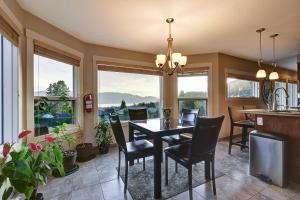 a dining room with a table and chairs and windows at Rodee Homestay in West Kelowna