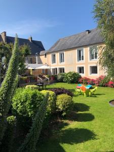 a large building with a yard with chairs and plants at Hôtel Le Gue Du Holme in Saint-Quentin-sur-le-Homme