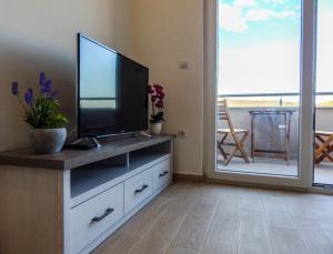 a living room with a flat screen tv on a dresser at Sweet Escape Apartments in Vinišće