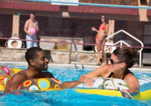 a man and woman riding on inflatables in a swimming pool at Pocono Palace Resort in East Stroudsburg