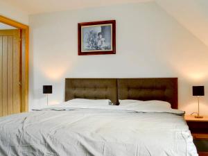 a bedroom with a large white bed with two lamps at The Coolins cottage with wood burner in Strathcarron