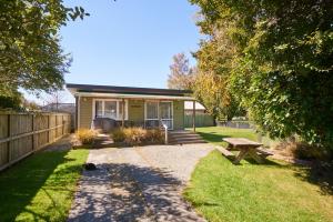 a small green house with a picnic table in the yard at Accommodation Fiordland The Bach - One Bedroom Cottage at 226B Milford Road in Te Anau