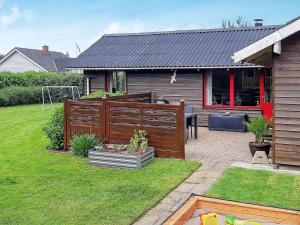a house with a wooden fence and a yard at 6 person holiday home in Hemmet in Hemmet