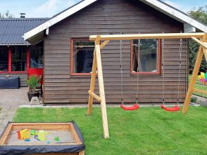a backyard with a swing set and a house at 6 person holiday home in Hemmet in Hemmet