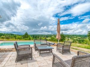 a patio with chairs and an umbrella next to a pool at Quaint Villa in Aquitaine with Swimming Pool in Saint-Alvère