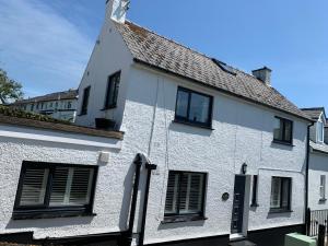 a white house with black windows on a street at Wogan Cottage in Saundersfoot