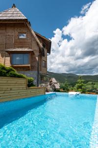 ein Haus mit einem Pool neben einem Gebäude in der Unterkunft Neva sobe sa pogledom na planine in Mokra Gora