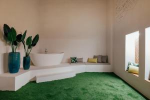 a bathroom with a white tub and a green rug at Hotel Cetina Sevilla in Seville