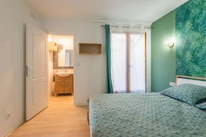 a bedroom with a bed and a bathroom with a sink at L'Exotique Narbonnais in Narbonne