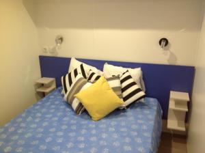 ein blaues Bett mit einem Haufen Kissen drauf. in der Unterkunft TopSun Argelès Camping La Sirène 2 bedroom 25m2 max 4 personnes Inc bebe pas d'enfants sans parents in Argelès-sur-Mer