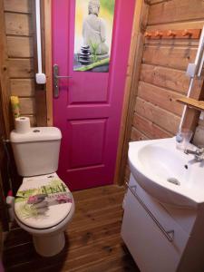 a bathroom with a toilet and a pink door at La Roulotte De Tina in Le Moule
