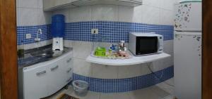 a small kitchen with blue tiles on the wall at Pousada Nascimentos -Pé na Areia- À 47 Passos do Mar in Bertioga +25 photos
