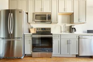 uma cozinha com armários brancos e um frigorífico de aço inoxidável em Sonder Telfair Square em Savannah