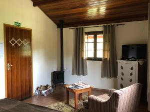 a living room with a couch and a table and a television at Pousada Vale dos Sonhos in Cunha