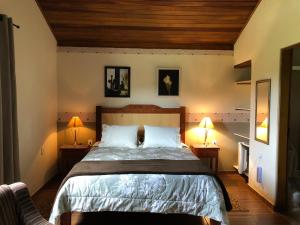 um quarto com uma cama e duas lâmpadas em duas mesas em Pousada Vale dos Sonhos em Cunha