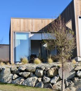 uma casa com uma parede de pedra e uma árvore em Lakeview Studio A - Lake Tekapo em Lake Tekapo