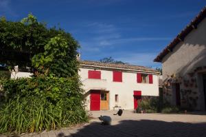 zwei Katzen, die vor einem Gebäude mit roten Türen sitzen in der Unterkunft Mas de la Lézardière — Maison d'Artiste in Manosque