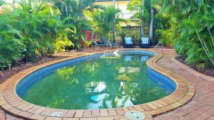 una piscina en un patio con árboles en Coconut Grove Holiday Apartments, en Darwin