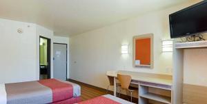 a hotel room with a desk and a bed and a television at Motel 6-Fort Lupton, CO in Fort Lupton