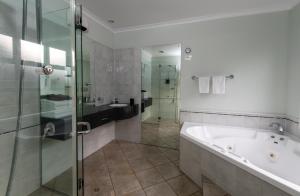 a bathroom with a tub and a glass shower at Cambridge Mews Motel in Cambridge