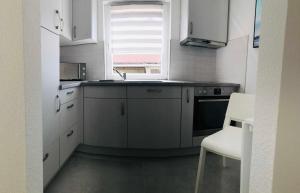 a kitchen with white cabinets and a sink and a chair at Ferienhaus Live Deluxe in der schönen Uckermark in Meyenburg