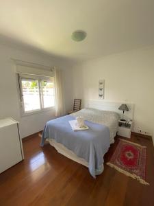 a white bedroom with a bed and a window at Pousada La Sierra in Campos do Jordão