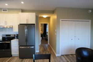a kitchen with a black refrigerator and white cabinets at Downtown Whitehorse Deluxe 2 Bedroom Condo in Whitehorse