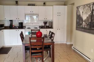 2-Bedroom Apartment Sweet #2 by Amazing Property Rentals في غاتينو: مطبخ به دواليب بيضاء وطاولة عليها كرة حمراء
