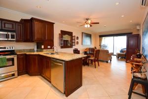 a kitchen with wooden cabinets and a living room at Exquisitely decorated 5th-floor aerie with views of two bays in Flamingo in Playa Flamingo