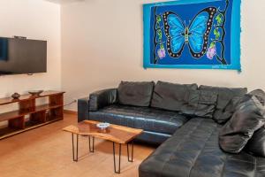sala de estar con sofá de cuero y pintura de mariposas en Nicely Priced Duplex in Surfside with Private Pool and AC in Every Room, en Potrero
