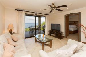 a living room with a white couch and a television at Luxury suite on 4th floor with pool and seemingly endless ocean views in Playa Flamingo