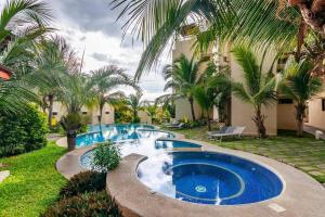 una piscina en un patio con palmeras en Colorful & Private 2-Bedroom Condo Just a Short Walk from the Beach, en Coco